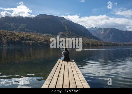 Sitzen Sie auf einem kleinen Steg und genießen Sie den Blick auf die Landschaft des Bohinj-Sees im Triglav-Nationalpark, die Julischen Alpen, Slowenien, Europa Stockfoto