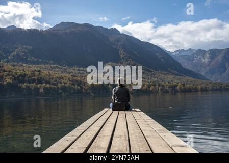 Sitzen Sie auf einem kleinen Steg und genießen Sie den Blick auf die Landschaft des Bohinj-Sees im Triglav-Nationalpark, die Julischen Alpen, Slowenien, Europa Stockfoto