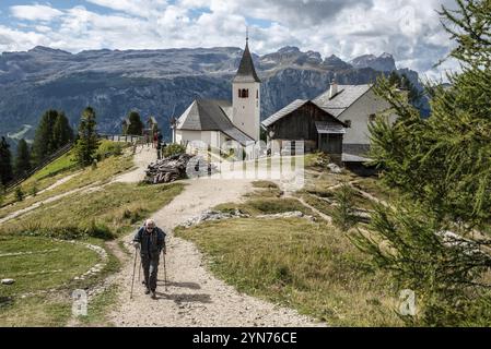 Ein älterer Wanderer in den Dolomiten, die Heilig Kreuz Kirche im Hintergrund, Südtirol in Italien Stockfoto