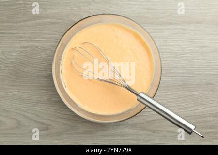 Schüssel mit Teig für Kürbispfannkuchen und Schneebesen auf Holztisch, Draufsicht Stockfoto