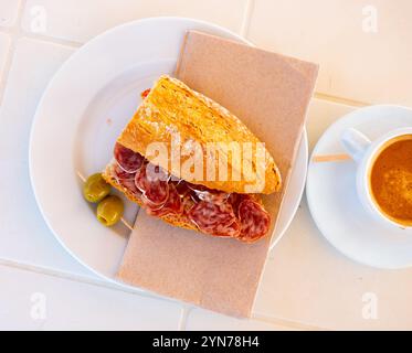 Spanisches Frühstück: Geräuchertes Würstchen-Fuet-Sandwich und Oliven in der Nähe Stockfoto