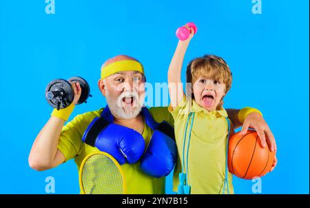 Sportliche Familie mit Sportausrüstung. Sportlicher Großvater und Enkel in Sportbekleidung. Lächelnder alter bärtiger Mann mit Hantel und Boxhandschuhen. Niedlich Stockfoto