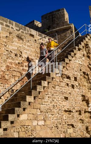 Zwei Personen steigen verwitterte Steintreppen hinauf und genießen das warme Sonnenlicht in einer historischen Bastion. Stockfoto
