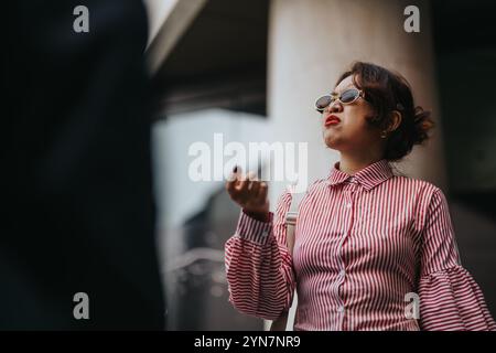 Selbstbewusste Geschäftsfrau in gestreiftem Hemd mit Sonnenbrille im Freien Stockfoto