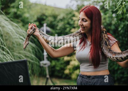 Mädchen, das mit großer Schlange in üppiger Umgebung interagiert Stockfoto