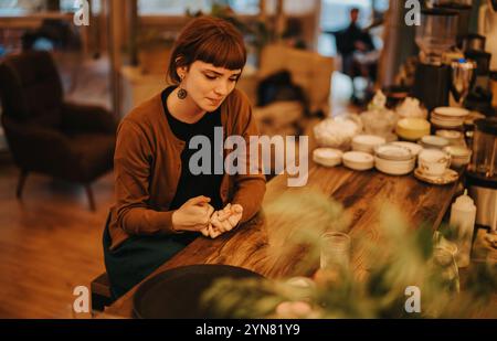 Eine nachdenkliche Frau sitzt allein an einem gemütlichen Café-Theke Stockfoto