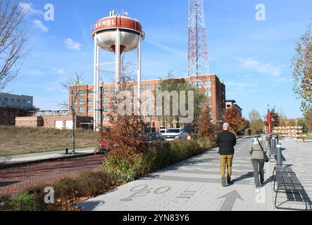 Ältere Ehepaare gehen auf dem Monon Greenway Trail in Carmel, Indiana, mit dem Stadtwasserturm im Hintergrund Stockfoto