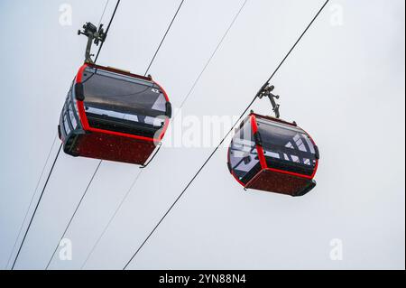 Rote Kabinen der Seilbahn in den Bergen im Nebel im Regen Stockfoto