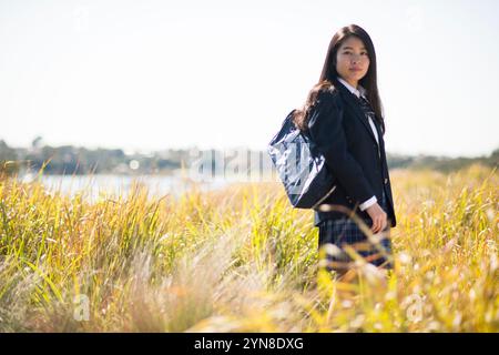 Highschool-Mädchen in Uniform, das auf Gras steht Stockfoto