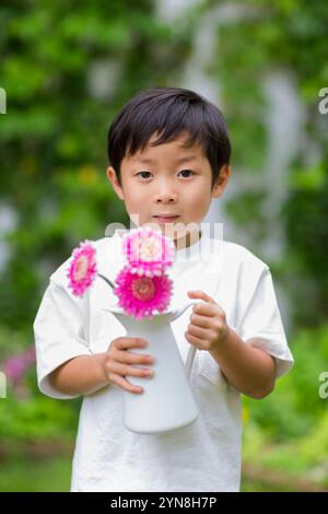 Kind, das Blumen in einer Vase im Garten hält Stockfoto