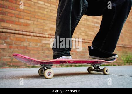 Skateboarder macht Tricks auf der Stadtstraße. Nahaufnahme eines Skaters mit Baggy-Jeans, der auf dem Skateboard balanciert. Konzept der Jugendsubkultur Stockfoto