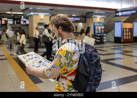 Touristen lesen eine Karte in einem geschäftigen japanischen Bahnhof Stockfoto