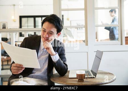 Ein lächelnder Mann in seinen 20ern, der Dokumente durchsucht Stockfoto
