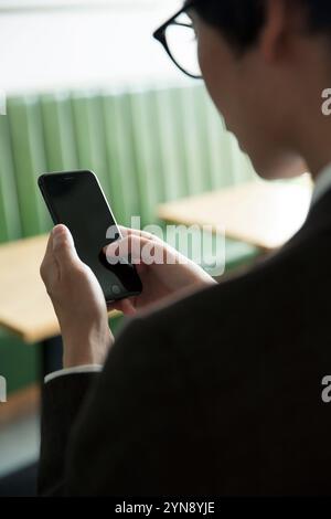 Rückansicht eines Mannes, der ein Smartphone bedient Stockfoto