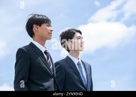 Zwei Männer in ihren 20ern in Anzügen, die auf dem Dach stehen Stockfoto