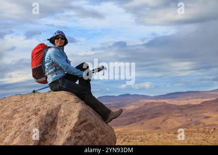 Junge Wanderer, die auf einem Berg sitzt und einen spektakulären Blick auf die isländische Landschaft genießt Stockfoto