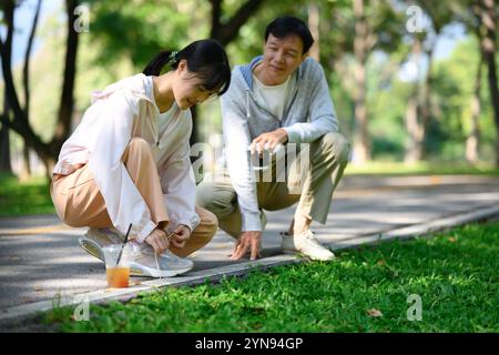 Vater und Tochter binden Schnürsenkel, bevor sie in einem wunderschönen Park joggen. Gesundheits- und Wohlfühlkonzept Stockfoto