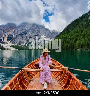 Eine junge Frau gleitet friedlich auf einem Holzboot und genießt einen Moment der Ruhe an einem atemberaubenden Bergsee, umgeben von hohen Gipfeln und üppigen Wäldern, Lago Di Prags Dolomiten Italien Stockfoto