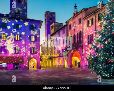 Abendlicher festlicher Stadtplatz, umgeben von historischen Gebäuden, beleuchtet und für Weihnachten dekoriert in Alba, Italien. Stockfoto