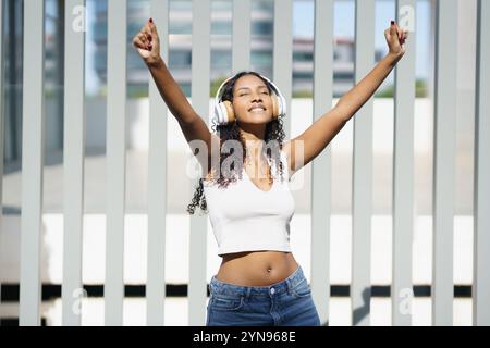 Eine freudige junge Frau genießt Musik in einer urbanen Umgebung voller Leben und Energie Stockfoto