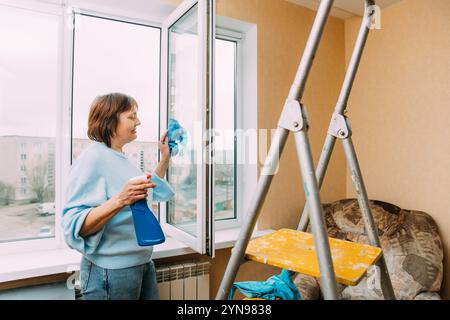 Active Seniors-Konzept. Glückliche Schüchterne, Fröhlich Lächelnde Reife Frau, Die Das Fenster Reinigt. Kaukasische Frau Im Mittleren Alter. Hausfrau. Reinigung Älterer Frauen Stockfoto