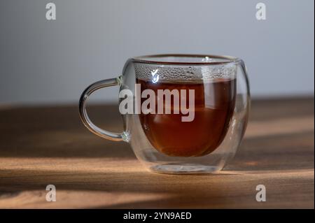 Das angenehme Aroma frisch gebrühten Tees erfüllt die Luft, während das Sonnenlicht auf der Glasschale tanzt. Stockfoto