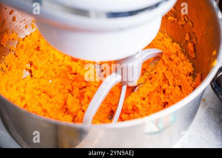 Das Verfahren zur Herstellung von Karottenpüree in einem Planetenmischer. Gesundes, diätetisches und vegetarisches Lebensmittelkonzept. Nahaufnahme. Hochwertige Fotos Stockfoto