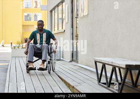 Porträt eines erwachsenen afroamerikanischen Mannes in voller Länge, der eine Rampe in zugänglicher Stadtumgebung benutzt und sich in Richtung Kamera im Freien auf den Kopierraum bewegt Stockfoto