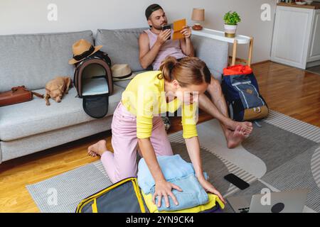 Ein junges Paar, das Reisetaschen für einen Urlaub in der Wohnung packt. Stockfoto