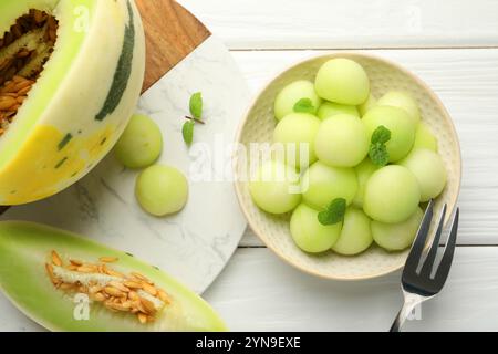 Melonenkugeln in der Schüssel und frisches Obst auf weißem Holztisch, flach gelegt Stockfoto