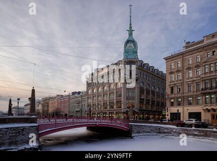 Sankt Petersburg, Russland - 8. Januar 2022: Rote Brücke über den Fluss Moika und ein altes Kaufhaus mit einem Turm Stockfoto