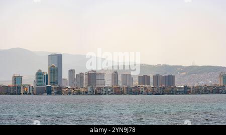 Izmir, Türkei - 3. Juli 2024: Blick auf die Kordon Street, den Fährpier und die Hochhäuser vom Meer aus in der Izmir Passport Gegend Stockfoto