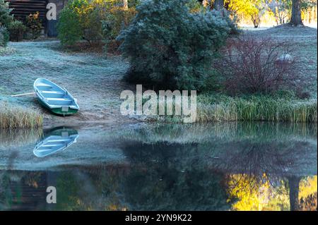 Kalte Herbstlandschaft am Morgen mit einem Boot am Ufer eines Sees oder Teichs in Lettland Stockfoto