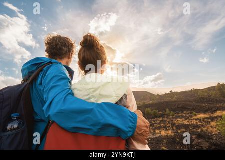 Erwachsenes Paar, das den Sonnenuntergang in den Bergen beobachtet, Rückansicht der Wanderer, die während der Abenteuerreise romantische Momente teilen Stockfoto