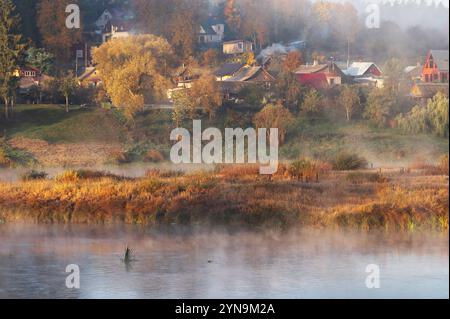 Herbstlich nebeliger Morgenblick über den Fluss Daugava zu den Dächern von Häusern der kleinen Stadt Krāslava in Lettland Stockfoto