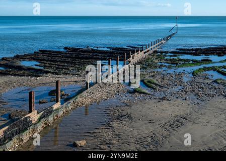 Wellenbrecher bei Ebbe an einem Sandstrand in England, mit ruhigem, blauem Wasser und niemandem dabei. November 2024. Stockfoto