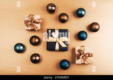Luxuriöse Weihnachtsliege mit Geschenkboxen, die mit goldenen Bändern und metallischen Ornamenten auf goldenem Hintergrund verbunden sind. Draufsicht, flach. Stockfoto