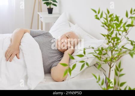 Pensionierter Seniorenmann, der morgens friedlich in einem bequemen weißen Bett schläft Stockfoto