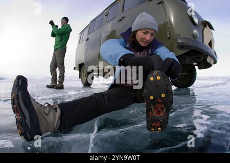 Eine Frau stellt ihre Steigeisen im Winter auf dem gefrorenen Baikalsee in Sibirien, Russland, ein. Stockfoto