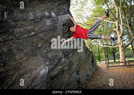 Ein junger Kletterer, der im Central Park Bouldern und Spaß hat. Stockfoto