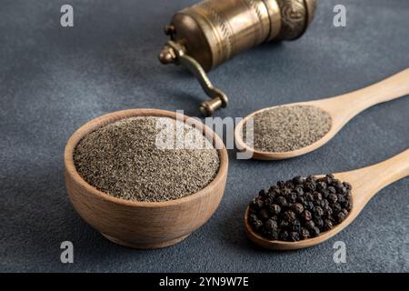 Schwarze Pfeffer, gemahlener schwarzer Pfeffer und Metallmühle auf schwarzem Hintergrund Stockfoto