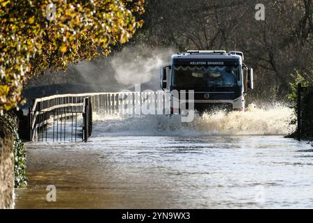 Lacock, Wiltshire, Großbritannien. November 2024. Der starke Regen des Sturms Bert hat den Fluss Avon in Lacock überschwemmt. Die Straße ist für alle bis auf die größten Fahrzeuge unpassierbar. Dieser Standort wird mehrmals im Jahr überschwemmt, aber heute ist das Wasser viel höher, und das Hochwasser erstreckt sich normalerweise nicht über den Damm hinaus, sondern hat es heute getan. Quelle: JMF News/Alamy Live News Stockfoto