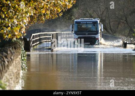 Lacock, Wiltshire, Großbritannien. November 2024. Der starke Regen des Sturms Bert hat den Fluss Avon in Lacock überschwemmt. Die Straße ist für alle bis auf die größten Fahrzeuge unpassierbar. Dieser Standort wird mehrmals im Jahr überschwemmt, aber heute ist das Wasser viel höher, und das Hochwasser erstreckt sich normalerweise nicht über den Damm hinaus, sondern hat es heute getan. Quelle: JMF News/Alamy Live News Stockfoto