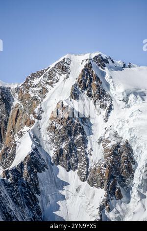 Die schneebedeckten Gipfel des Mont Blanc glitzern in der Sonne und ragen über üppige Täler. Der klare blaue Himmel schafft eine atemberaubende alpine Landschaft Stockfoto