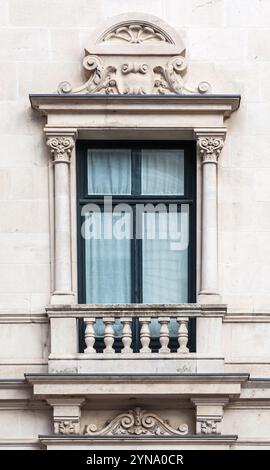 Ein wunderschön gearbeitetes Fenster mit verzierten Säulen und dekorativen Motiven zeigt die klassische Architektur eines Stadtgebäudes. Stockfoto