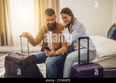 Das junge glückliche Paar ist im Urlaub. Touristen kamen mit ihren Koffern im Hotelzimmer an. Stockfoto