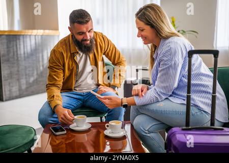 Das junge glückliche Paar geht in den Urlaub. Touristen sitzen in der Hotellobby und trinken Kaffee. Stockfoto