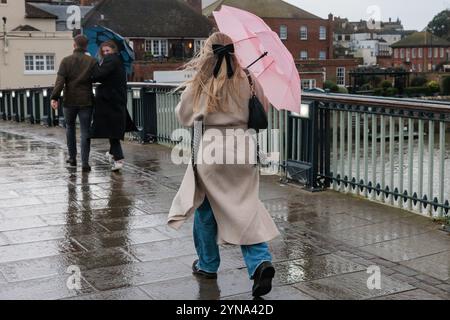 Windsor, Großbritannien. November 2024. Mitglieder der Öffentlichkeit verwenden Regenschirme, um sich während des Sturms Bert vor Wind und Regen auf der Windsor Bridge zu schützen. Eine gelbe Windwarnung wurde für Südengland und Teile von Wales ausgegeben. Quelle: Mark Kerrison/Alamy Live News Stockfoto