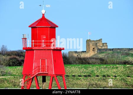 South Shields neu restaurierter, antiker Leuchtturm von Herd Sands mit Heritage Tynemouth Castle im Hintergrund vor einem blauen Himmel Stockfoto