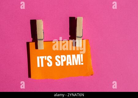 Es ist eine Spam-Nachricht, geschrieben auf zerrissenem orangenem Papierstück mit rosa Hintergrund. Konzeptionell ist das Spam-Symbol. Kopierbereich. Stockfoto